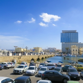 Typický pohled podél mostu s výškovou budovou z historického městečka do nové části města.